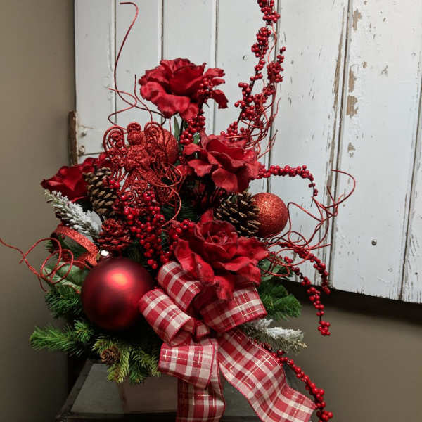 Red floral holiday arrangement with plaid ribbon, pinecones, and ornaments