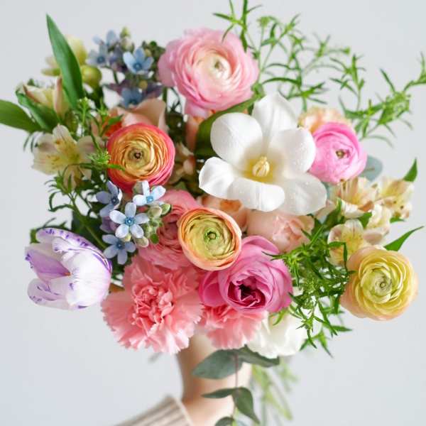 Handheld bouquet of pink, white, and pastel mixed flowers