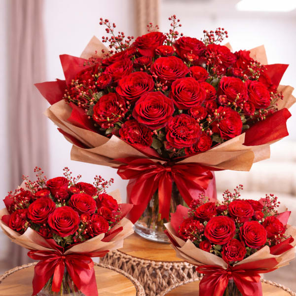 Three red rose bouquets wrapped in kraft paper with red ribbons