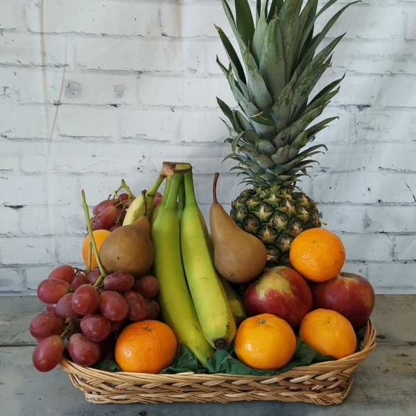Basket of assorted fruit with a pineapple, bananas, grapes, pears, oranges, and apples