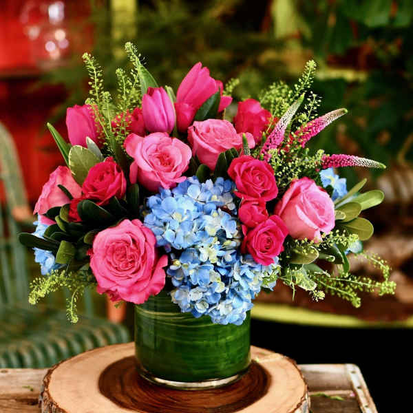 Pink roses and tulips with blue hydrangeas in a green vase