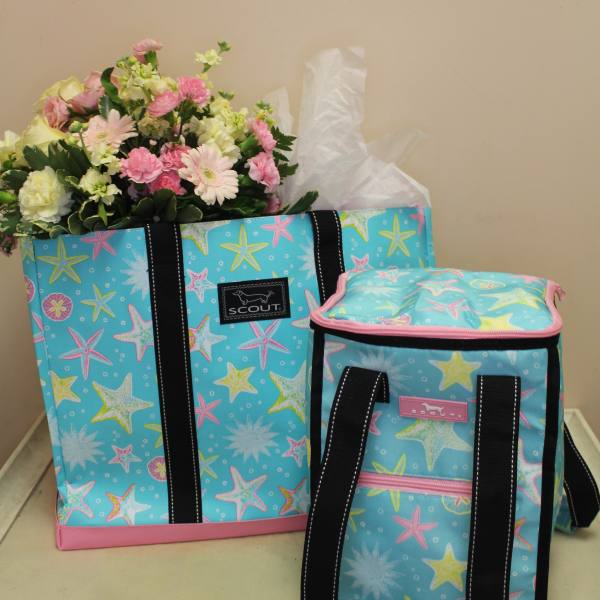 Bouquet of pink and white flowers in a patterned tote bag beside a matching cooler bag