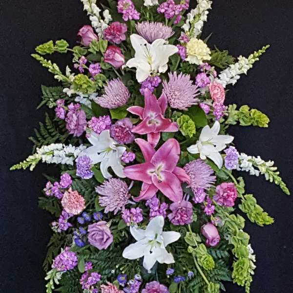 Standing floral spray with pink lilies, white lilies, and purple flowers