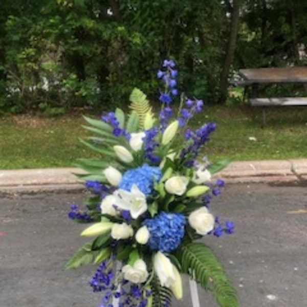 Tall blue and white floral standing arrangement on a white easel