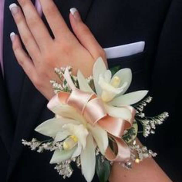 White corsage and boutonniere with ribbon on a dark suit