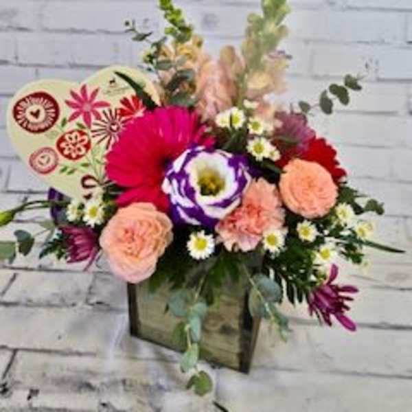 Mixed bouquet in a wooden box with pink, peach, and purple flowers