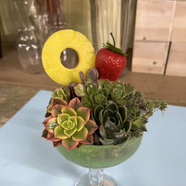 Succulent arrangement in a stemmed glass with a pineapple ring and strawberry garnish