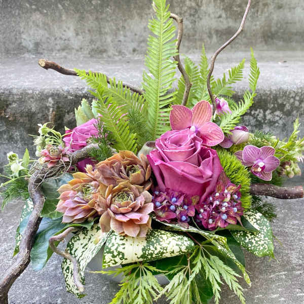 Pink roses and orchids arranged with succulents in a low container