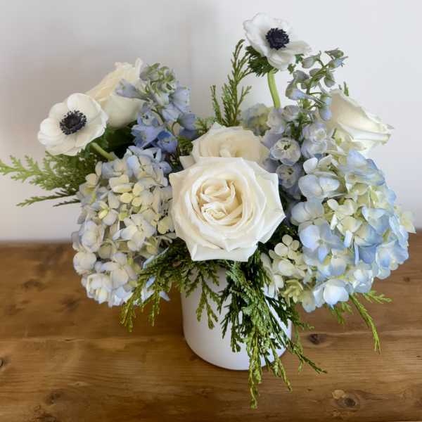 White roses and blue hydrangeas in a white vase
