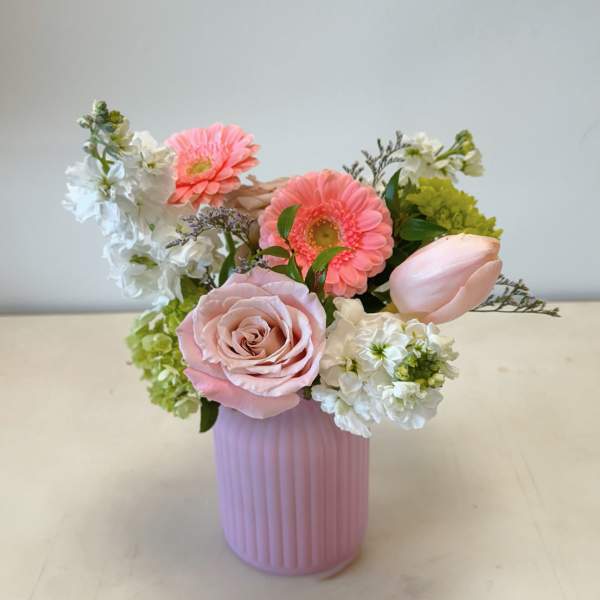 Pink and white flower arrangement in a ribbed pink vase