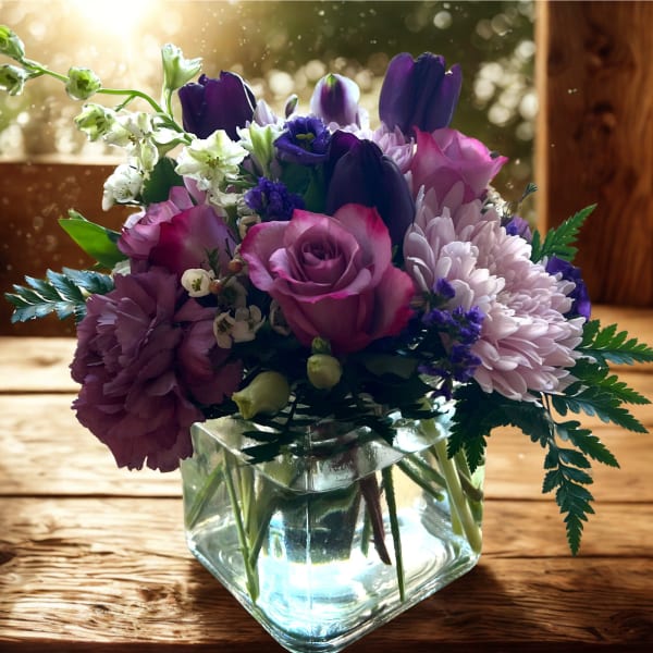 Purple and pink mixed bouquet in a clear glass vase