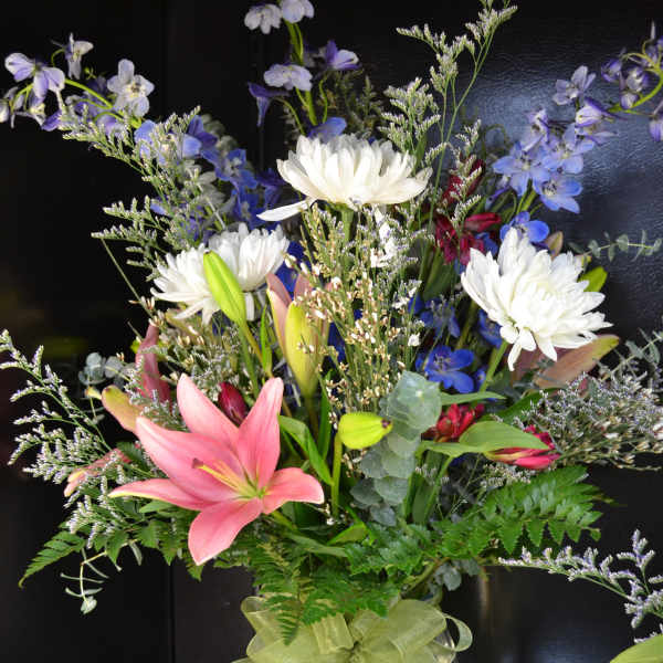 Mixed bouquet with pink lilies, white chrysanthemums, and blue flowers in a glass vase