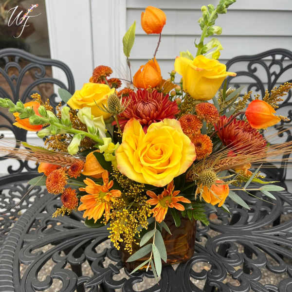 Yellow and orange flower arrangement in a brown glass vase