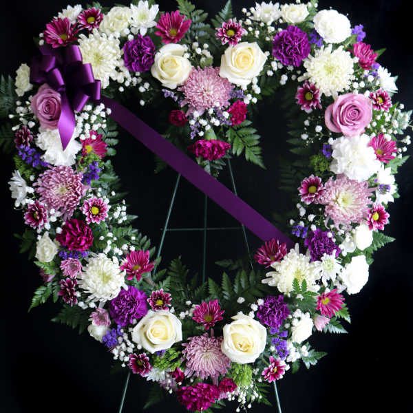 Heart-shaped floral wreath with purple ribbon on an easel