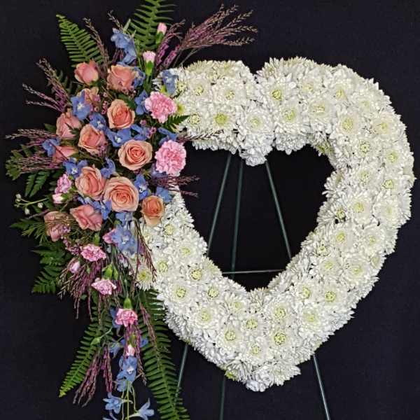 Heart-shaped white floral wreath with a pink and blue flower spray
