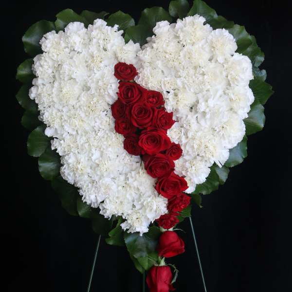 Heart-shaped white floral spray with red roses down the center