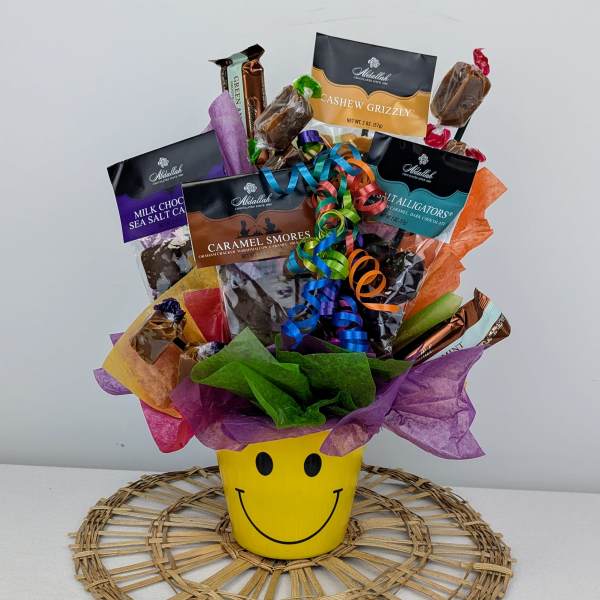 Candy bouquet in a yellow smiley-face cup with colorful wrappers