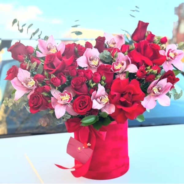 Red roses and pink orchids in a red wrapped bouquet