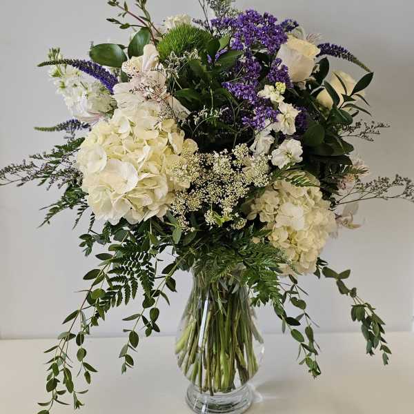 White and purple floral arrangement in a clear glass vase