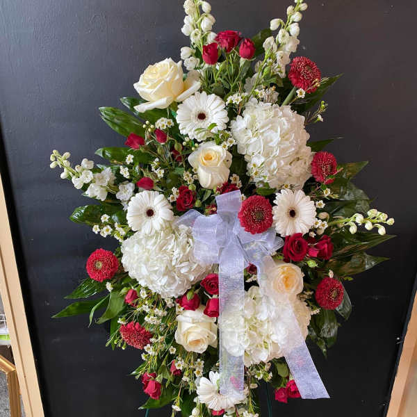 Standing floral spray with white and red flowers and a lavender ribbon