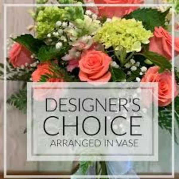 Coral roses and green hydrangeas in a vase with a designer's choice sign