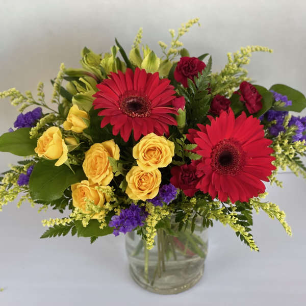 Bouquet of red gerbera daisies and yellow roses in a glass vase