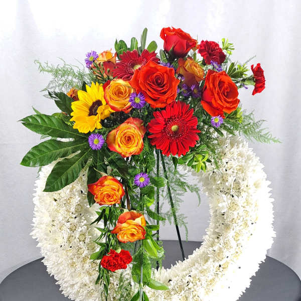 Standing floral wreath with red, orange, yellow, and white flowers