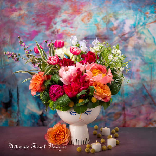 Colorful mixed bouquet in a white face vase with candles nearby