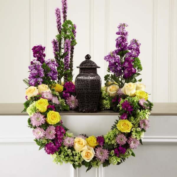 Purple and yellow floral wreath around a black urn