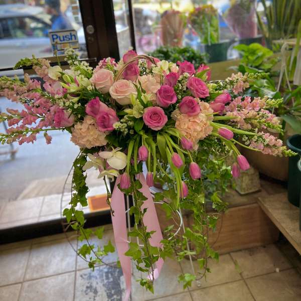 Pink and white floral arrangement with roses and tulips in a stand