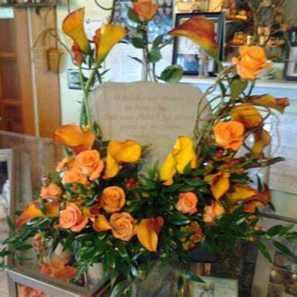 Orange roses and calla lilies arranged in a glass vase