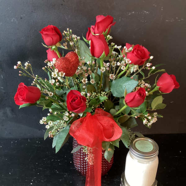Red roses in a red vase with a glittery heart pick and ribbon