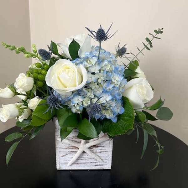 White roses and blue hydrangeas in a white wooden box