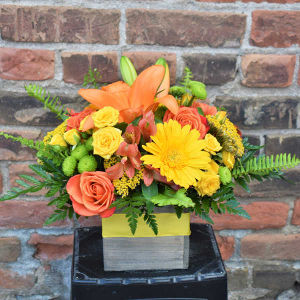 Orange lilies and yellow roses in a square box arrangement