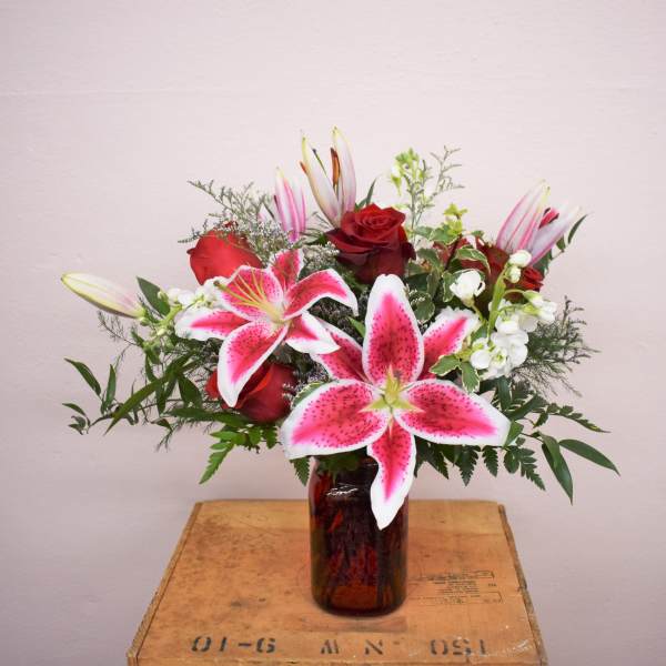 Bouquet of pink lilies and red roses in a glass vase