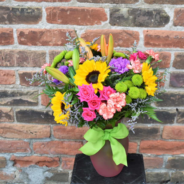 Colorful bouquet with sunflowers, roses, lilies, and carnations in a vase