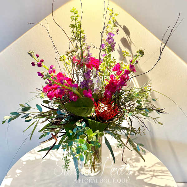 Tall mixed bouquet in a clear glass vase with bright pink and purple blooms