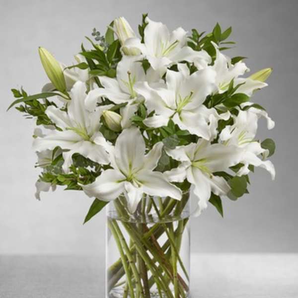 White lilies arranged in a clear glass vase