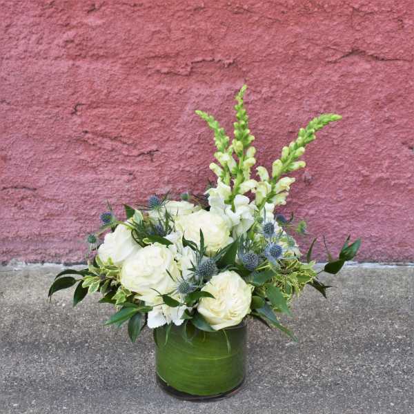 White roses and snapdragons in a green glass vase