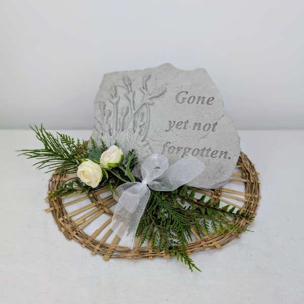 Memorial stone with white roses and greenery on a wicker base