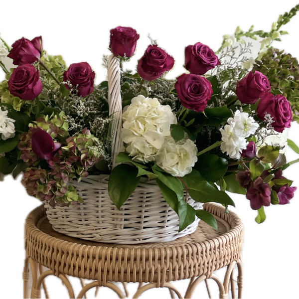 Basket arrangement of magenta roses, white hydrangeas, and white stock
