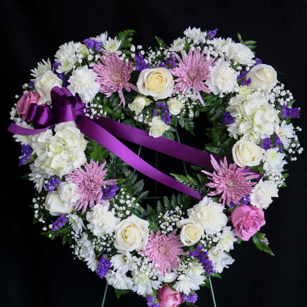 Heart-shaped floral wreath with pink and white flowers and a purple ribbon