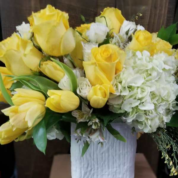 Yellow roses and white hydrangeas arranged in a white vase