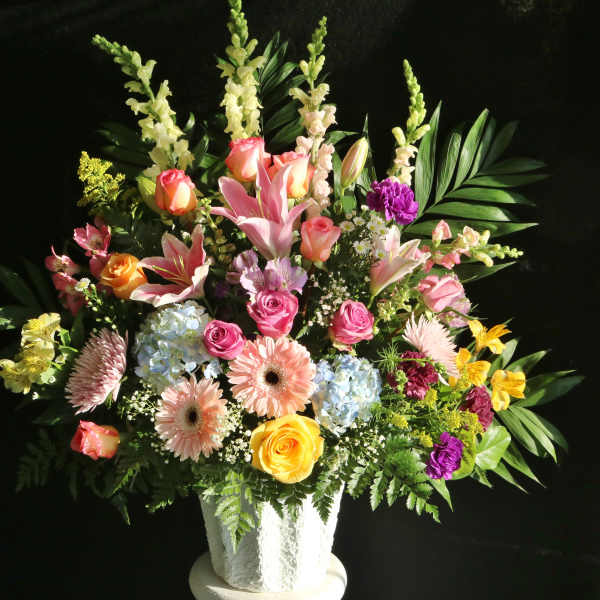 Mixed bouquet of roses, lilies, and gerbera daisies in a white vase