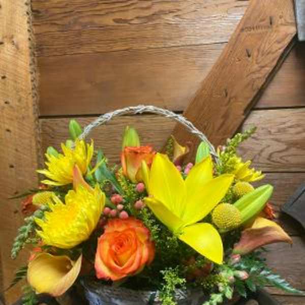 Basket arrangement of yellow lilies, orange roses, and yellow daisies