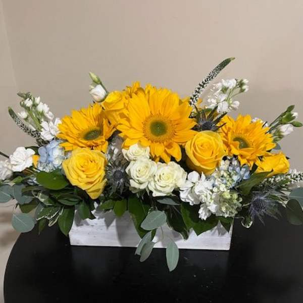 Yellow sunflowers and roses in a white rectangular box