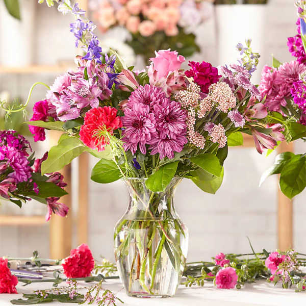 Mixed pink and purple flowers arranged in a clear glass vase