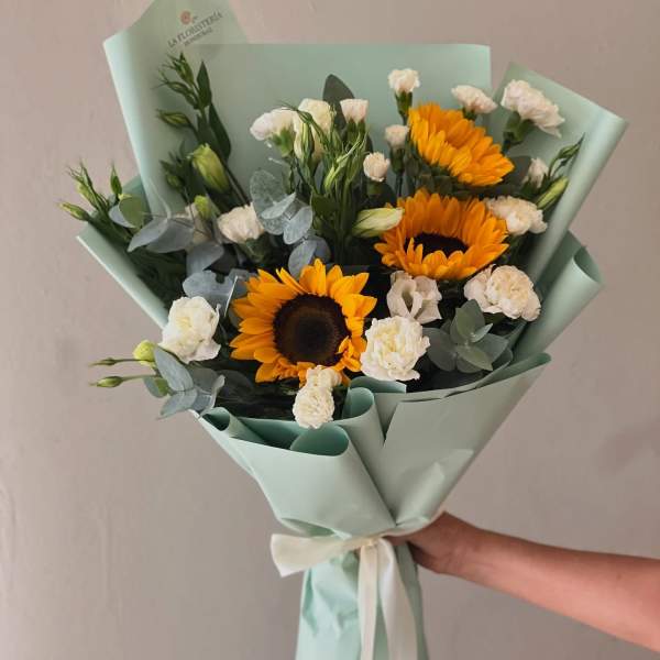 Bouquet of sunflowers and white carnations wrapped in pale mint paper