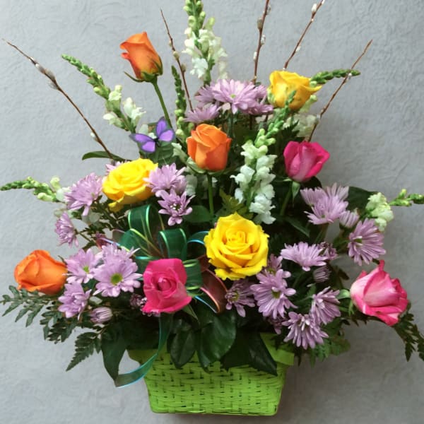 Mixed bouquet of roses and purple daisies in a green basket