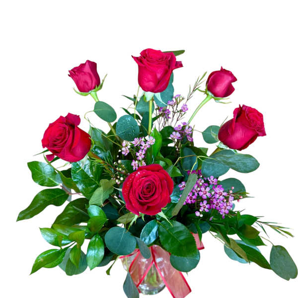 Vase arrangement of red roses with small pink filler flowers in a clear glass vase with red ribbon